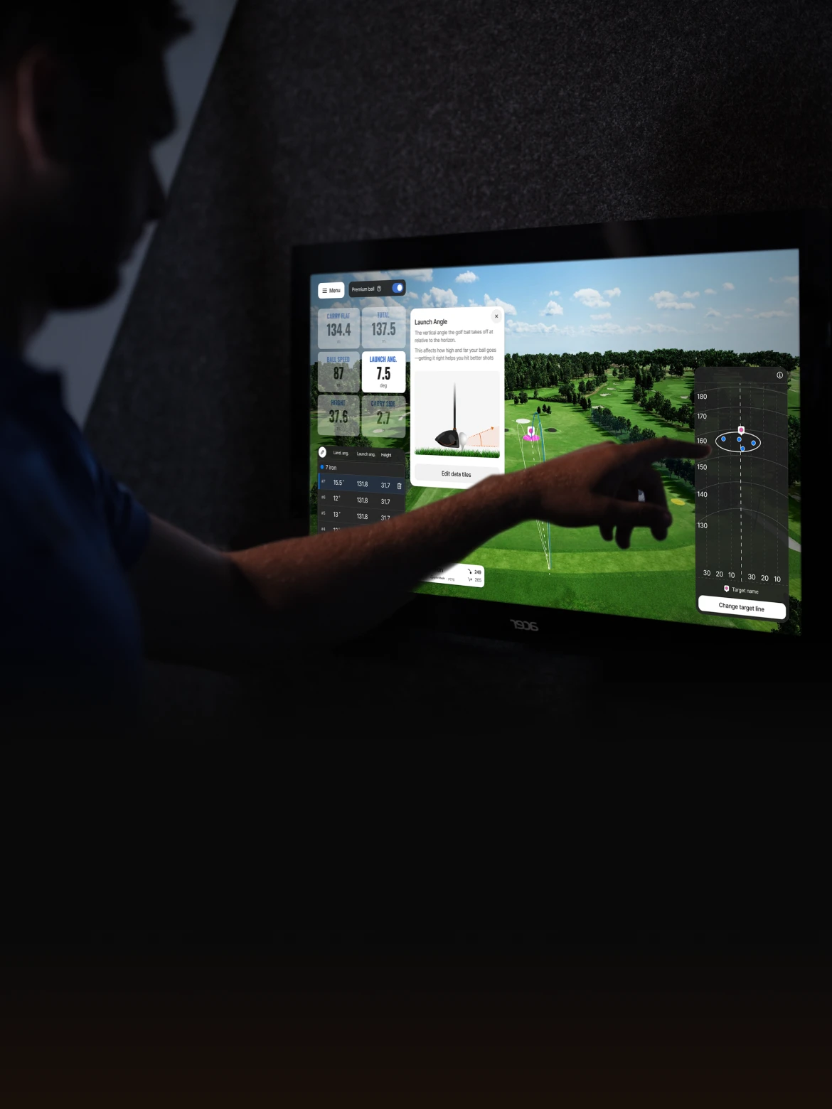 A person uses a touchscreen displaying golf analytics, including launch angle, on a virtual golf course interface.