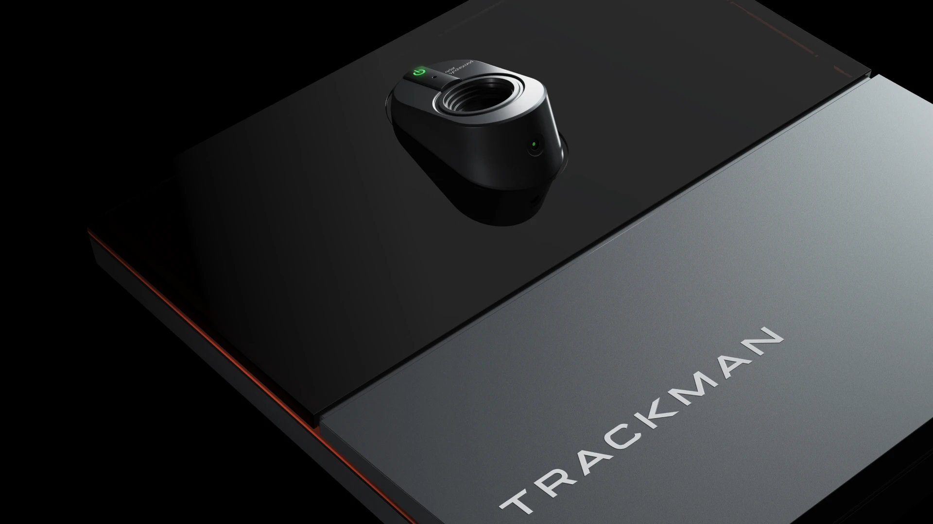 A close-up view of a sleek, modern black device labeled "TRACKMAN," featuring a distinct, circular sensor or camera on a glossy surface.