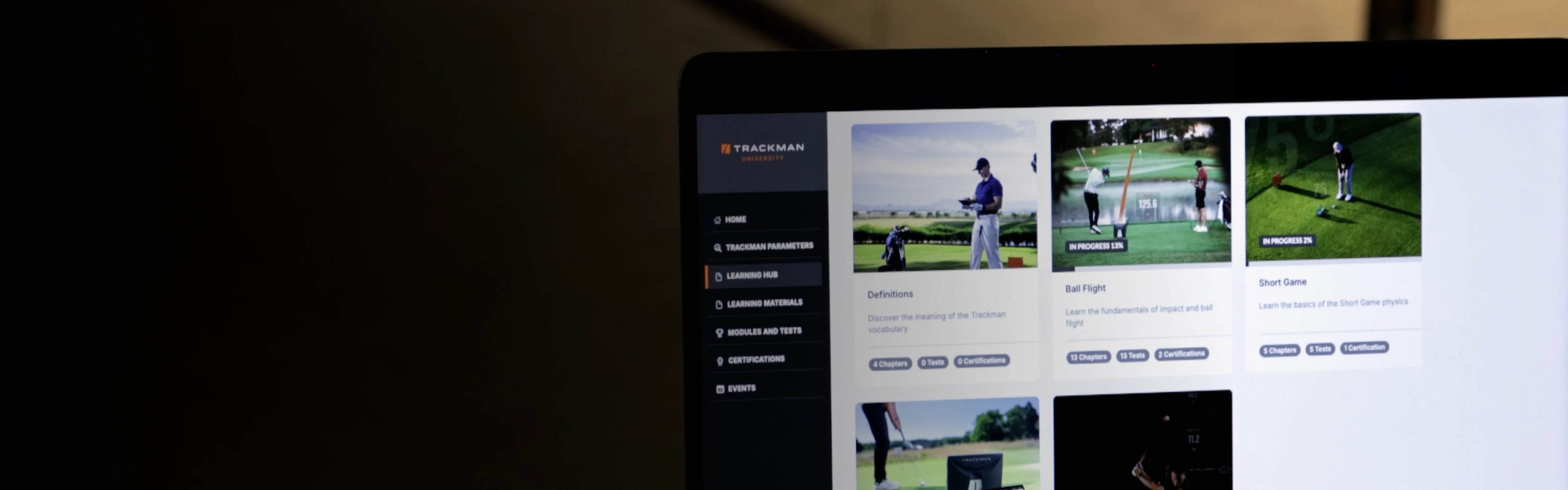 Laptop screen displaying a golf training program with menu options on the left and video thumbnails on the right.