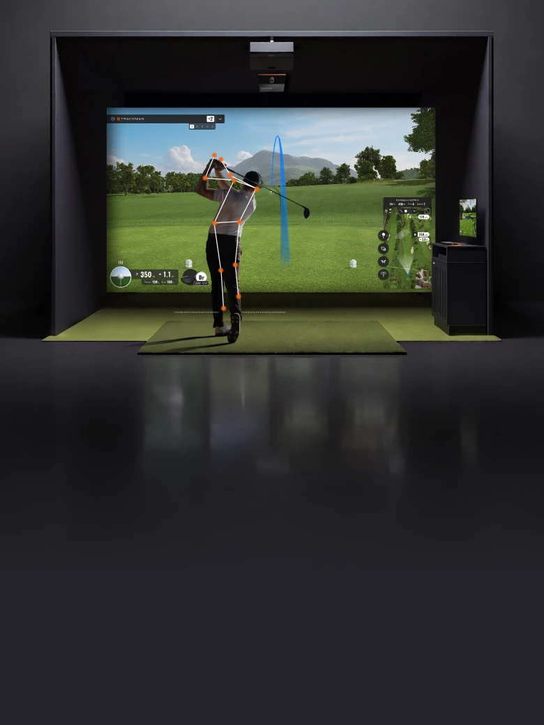 Golfer using an indoor simulator, captured mid-swing, with virtual landscape and data displayed on a large screen, indicating shot trajectory.