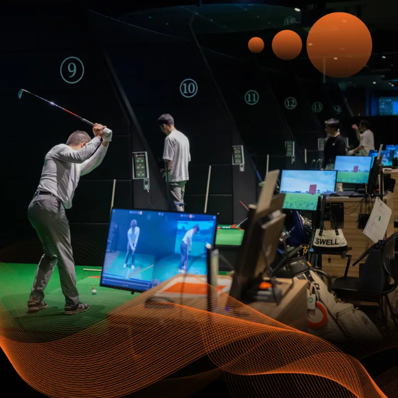 Two people in a golf simulation room practicing swings, with screens displaying their movements. Orange wave and sphere design overlay.