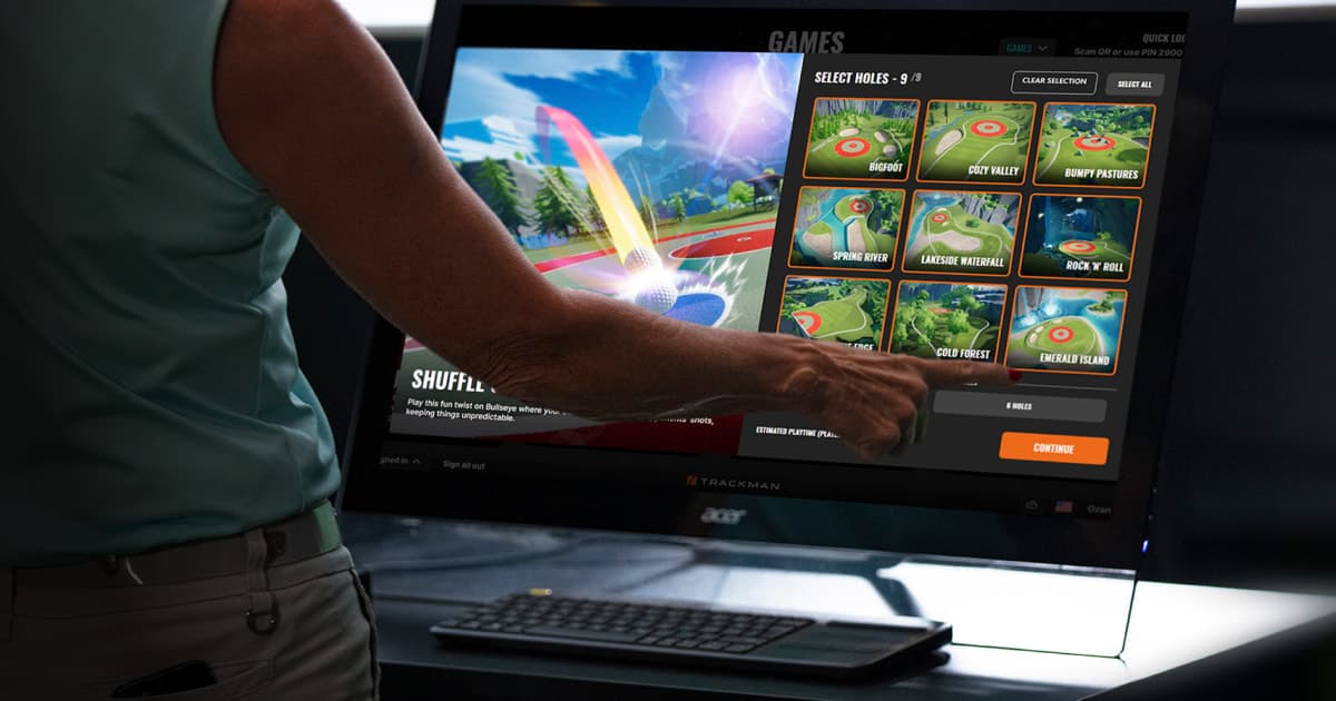 Person interacting with a touchscreen displaying a golf game interface, selecting various courses with vibrant graphics on a large monitor.