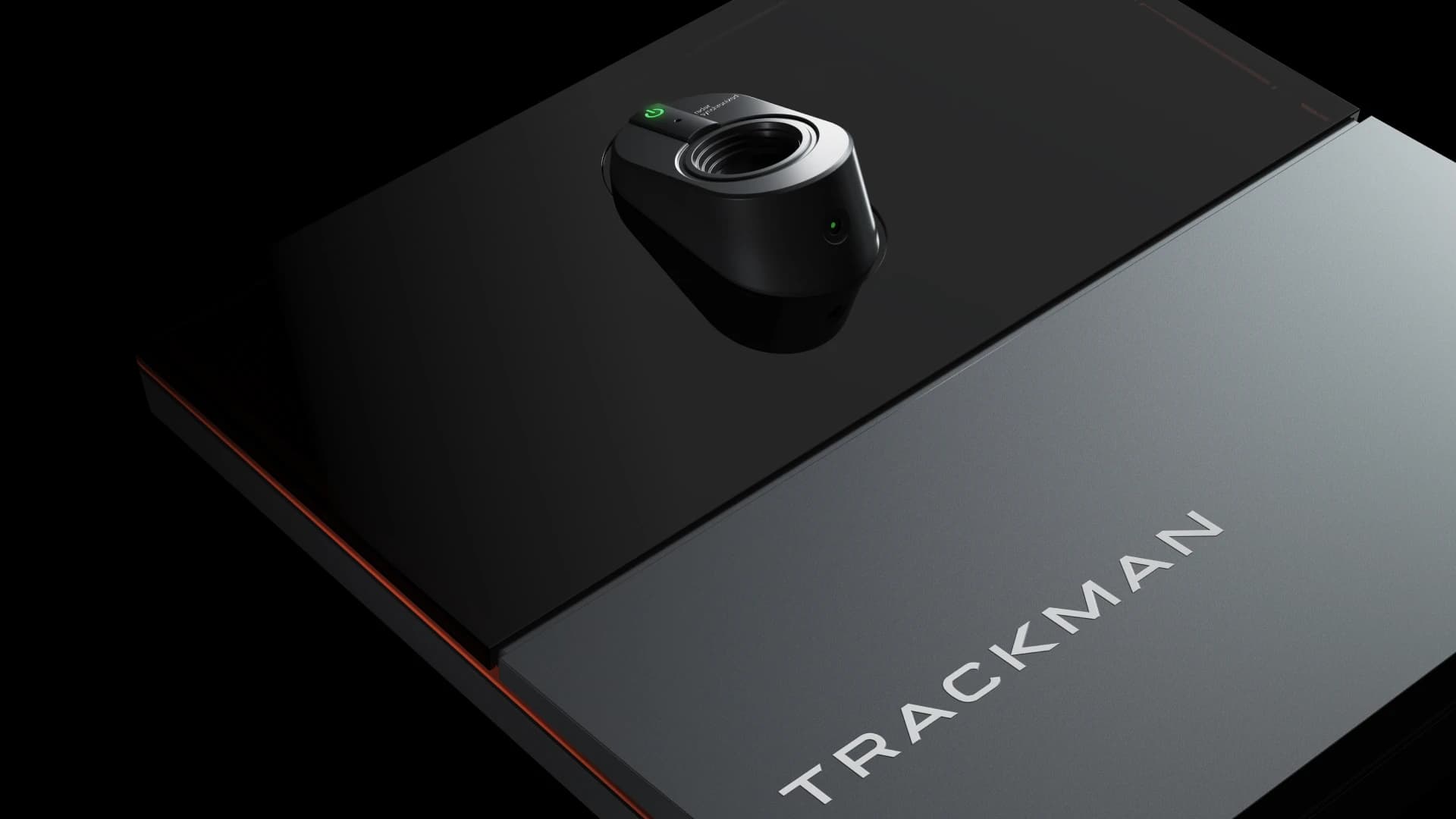 A close-up view of a sleek, modern black device labeled "TRACKMAN," featuring a distinct, circular sensor or camera on a glossy surface.