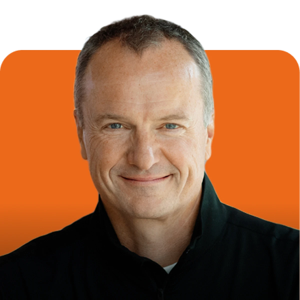 Close-up portrait of a smiling middle-aged man against an orange background, wearing a black jacket.