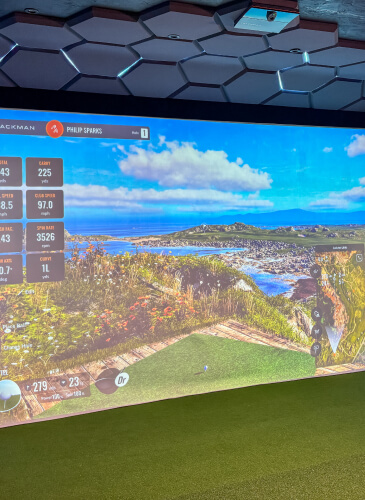 Trackman Indoor golf simulator displaying a coastal golf course with performance stats